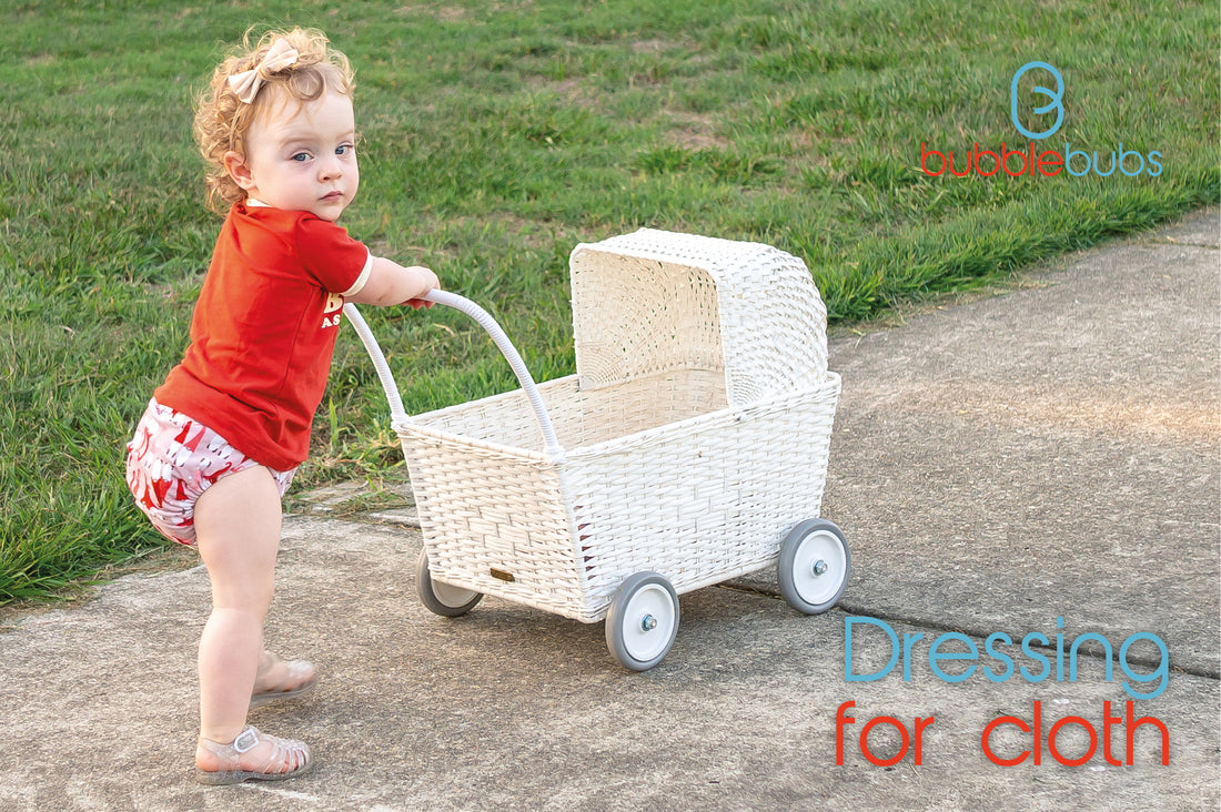 Little-girl-pushing-a-white-pram-and-wearing-a-red-shirt-with-a-modern-cloth-nappy-and-jelly-sandals