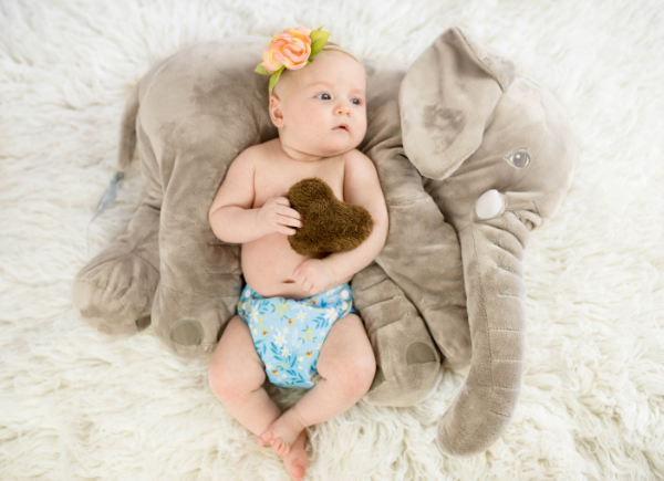 newborn baby on a elefant toy in a blue candie cloth nappy