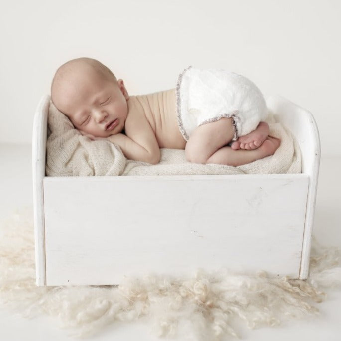 newborn resting in a crib wearing a Bambam fitted cloth nappies