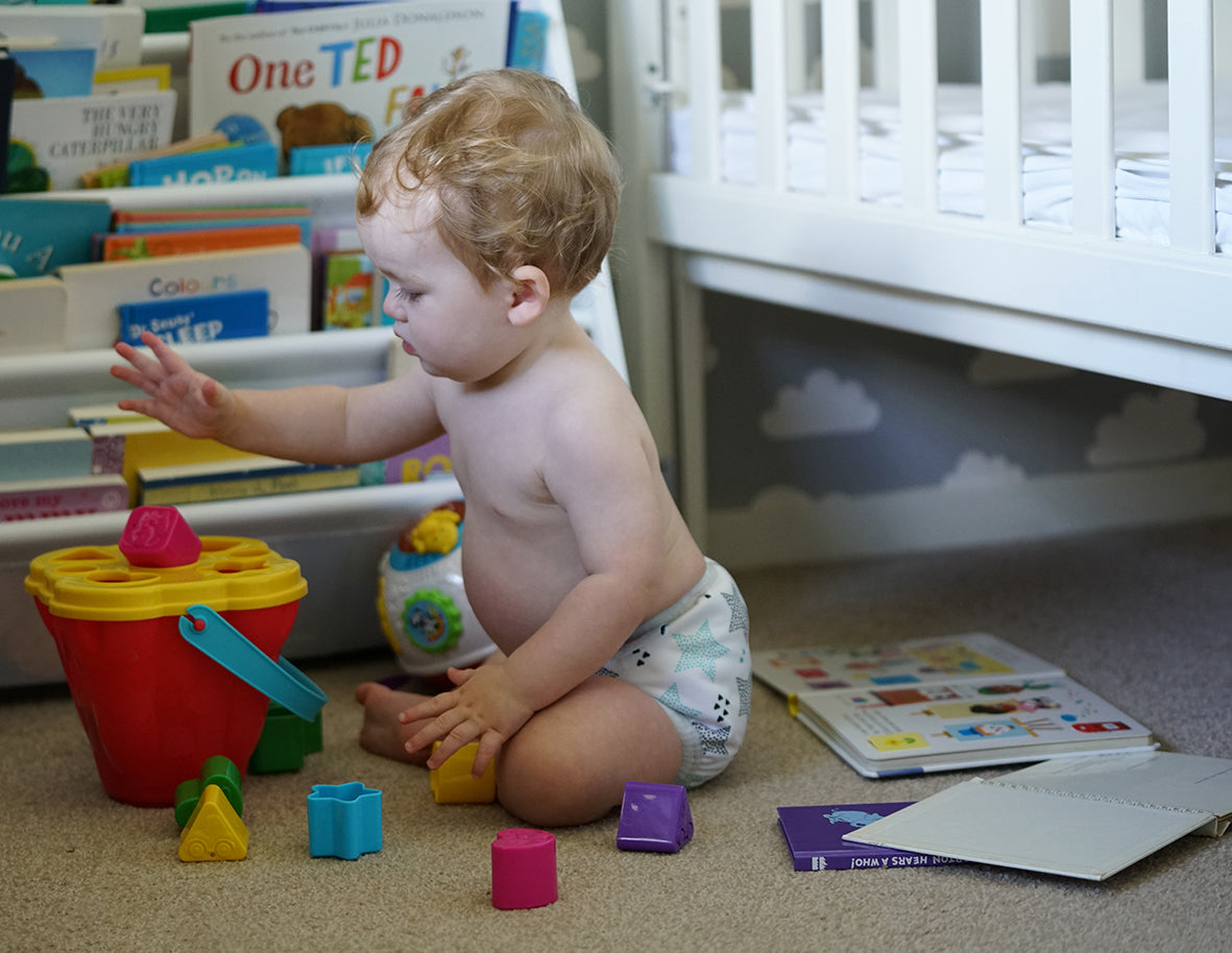 baby playing with blocks wearing cloth nappy prefold