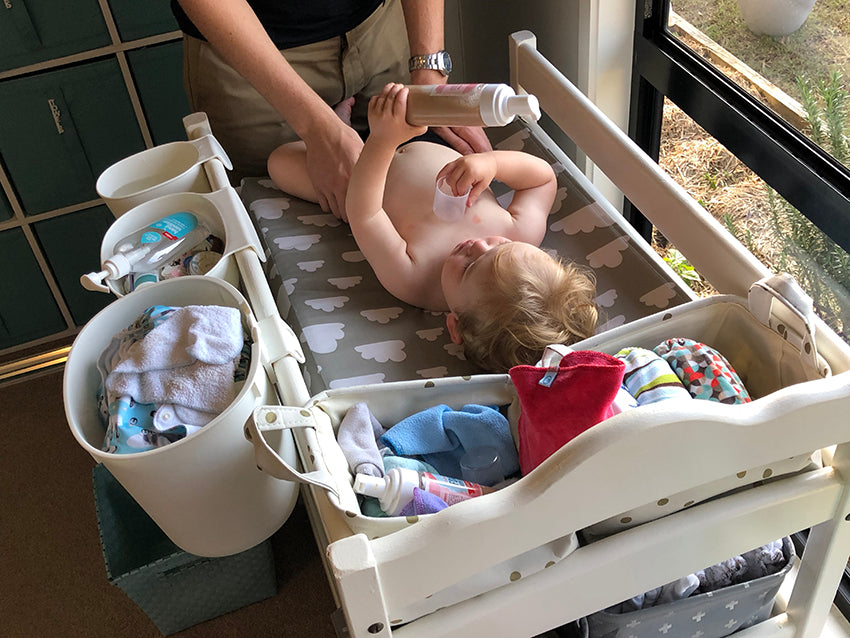 Baby having his modern cloth nappy changed by his father on a change table