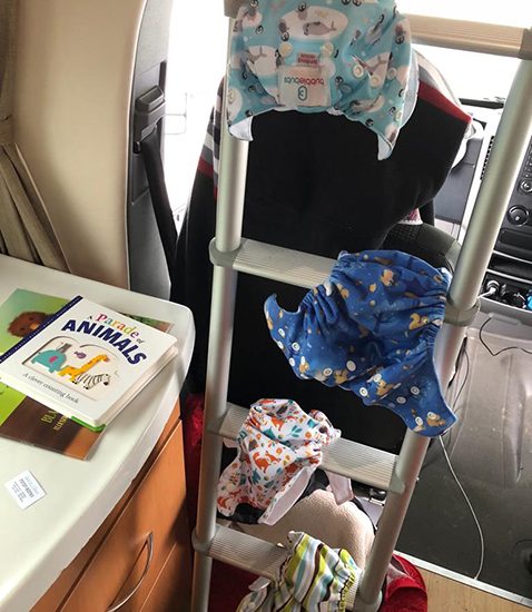 Modern cloth nappy shells hanging to dry on a ladder in a campervan.