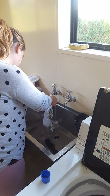 Mother washing cloth nappies in a sink at campsite.