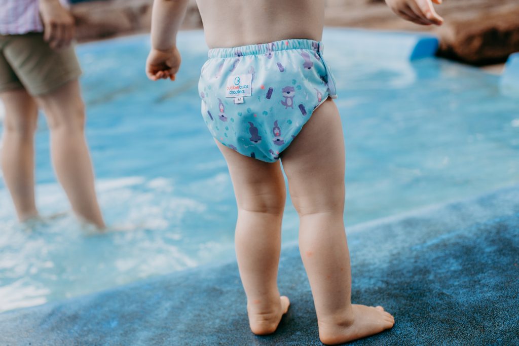 Toddler wearing a bubblebubs droplets swim nappies with otters on it.