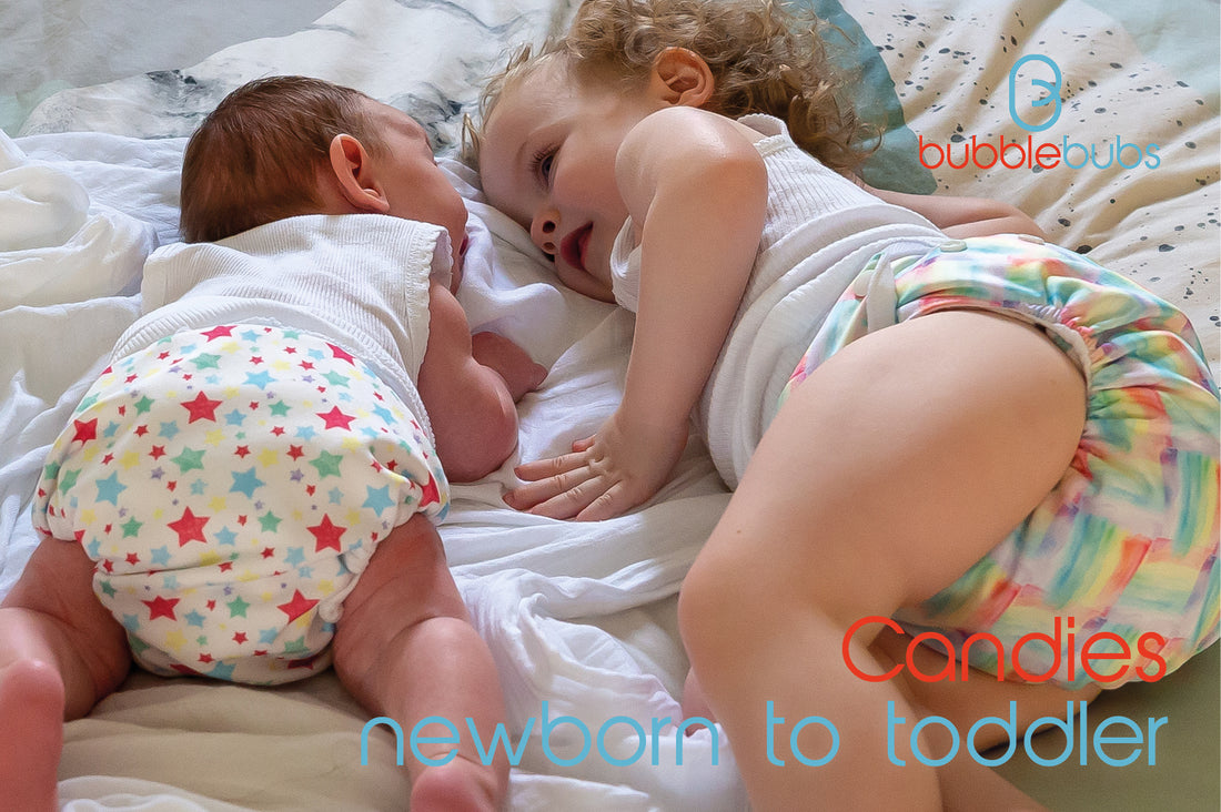 A-newborn-and-a-toddler-laying-on-a-bed-wearing-candie-modern-cloth-nappies
