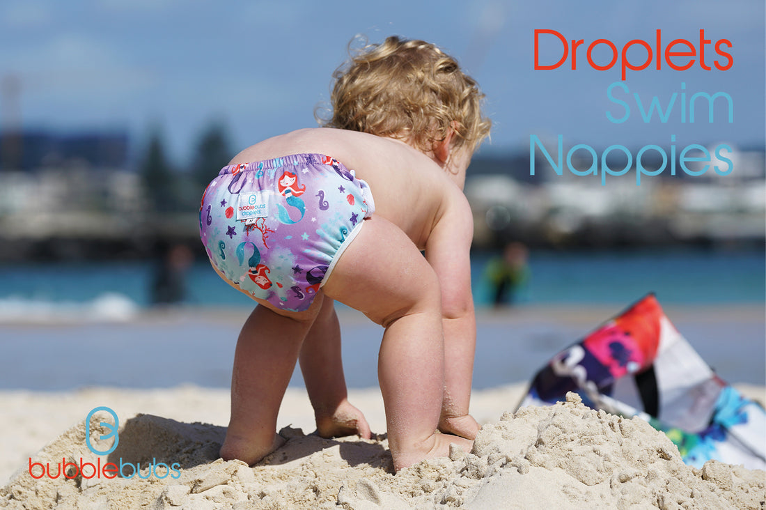 Toddler-playing-at-an-Australian-beach-wearing-a-reusable-swim-nappy-with-mermaids-on-it