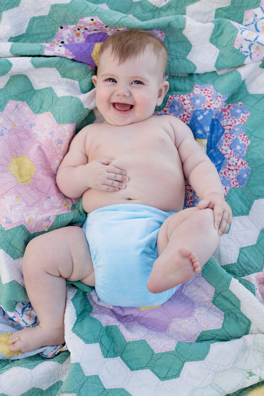 blue candie cloth nappy on a happy baby on a rug