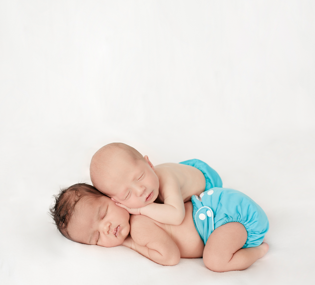 two sleeping babies wearing blue cloth nappies, one with dark hair and the other with no hair