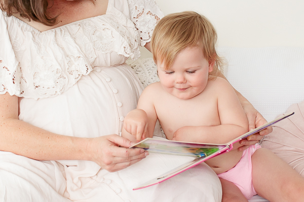 mother reading to her toddler who has a pink cloth nappy on and is turning the pages